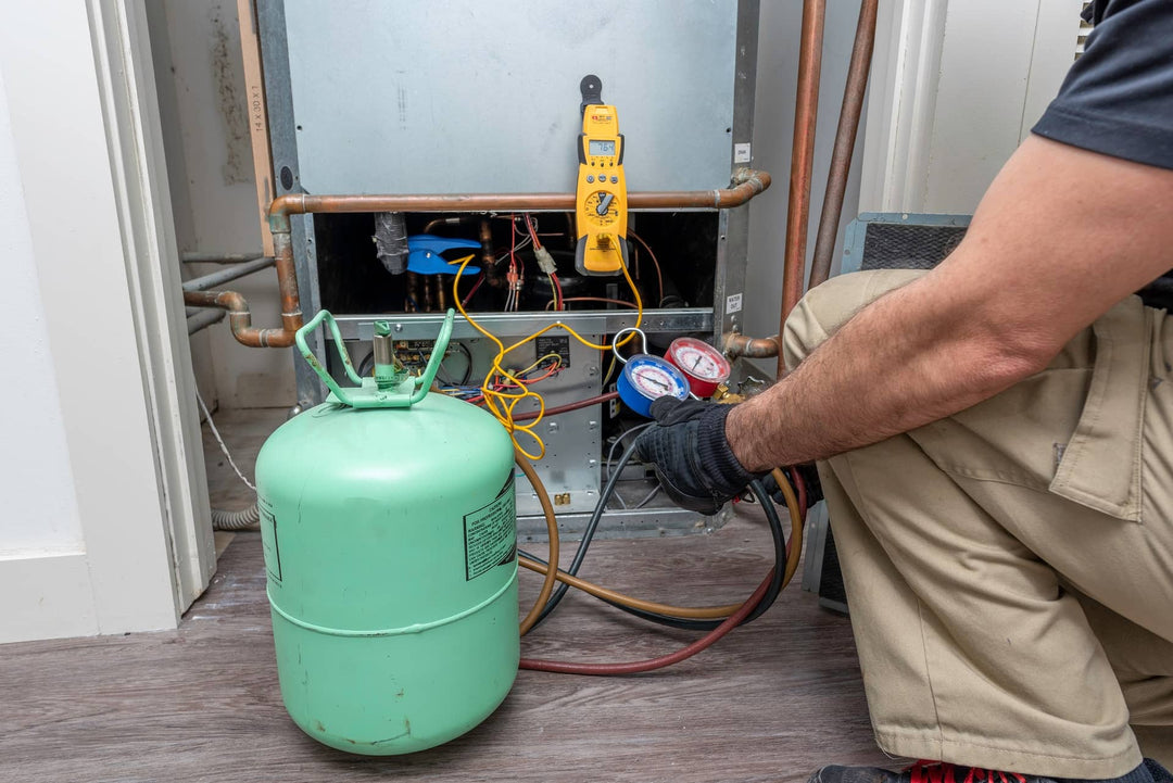 A technician using a manifold gauge to check refrigerant levels in an air conditioning system.