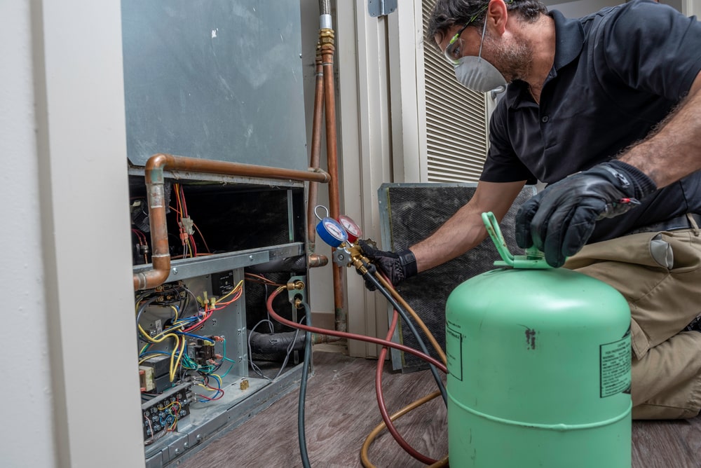 A technician using an electronic detector to locate refrigerant leaks in an HVAC system.